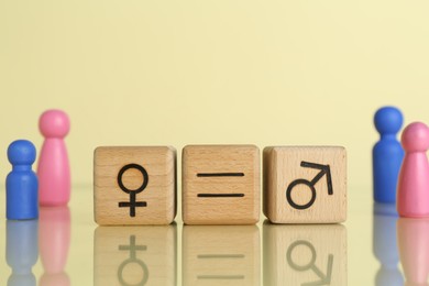 Gender equality concept. Wooden cubes with male and female symbols on light yellow background