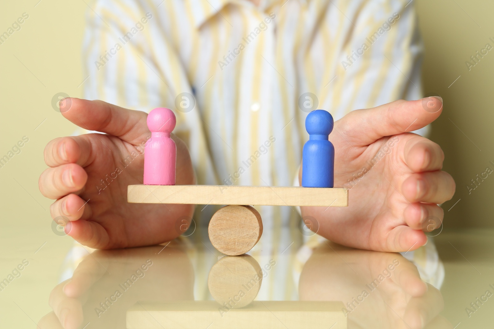 Photo of Gender equality concept. Woman with male and female figures on scales against light yellow background, closeup