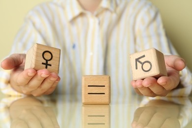 Gender equality concept. Woman with wooden cubes of male and female symbols at table, closeup