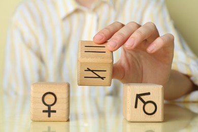 Gender equality concept. Woman with wooden cubes of male and female symbols at table, closeup