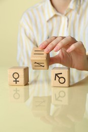 Photo of Gender equality concept. Woman with wooden cubes of male and female symbols at table, closeup