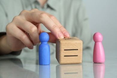 Gender equality concept. Woman with male and female figures at grey table, closeup