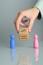 Gender equality concept. Woman with male and female figures at grey table, closeup