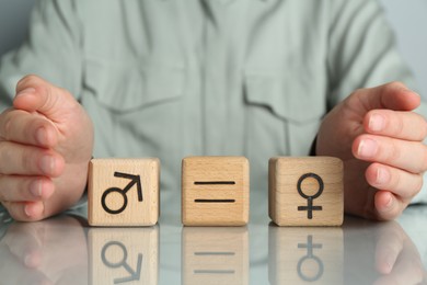 Gender equality concept. Woman with wooden cubes of male and female symbols at table, closeup