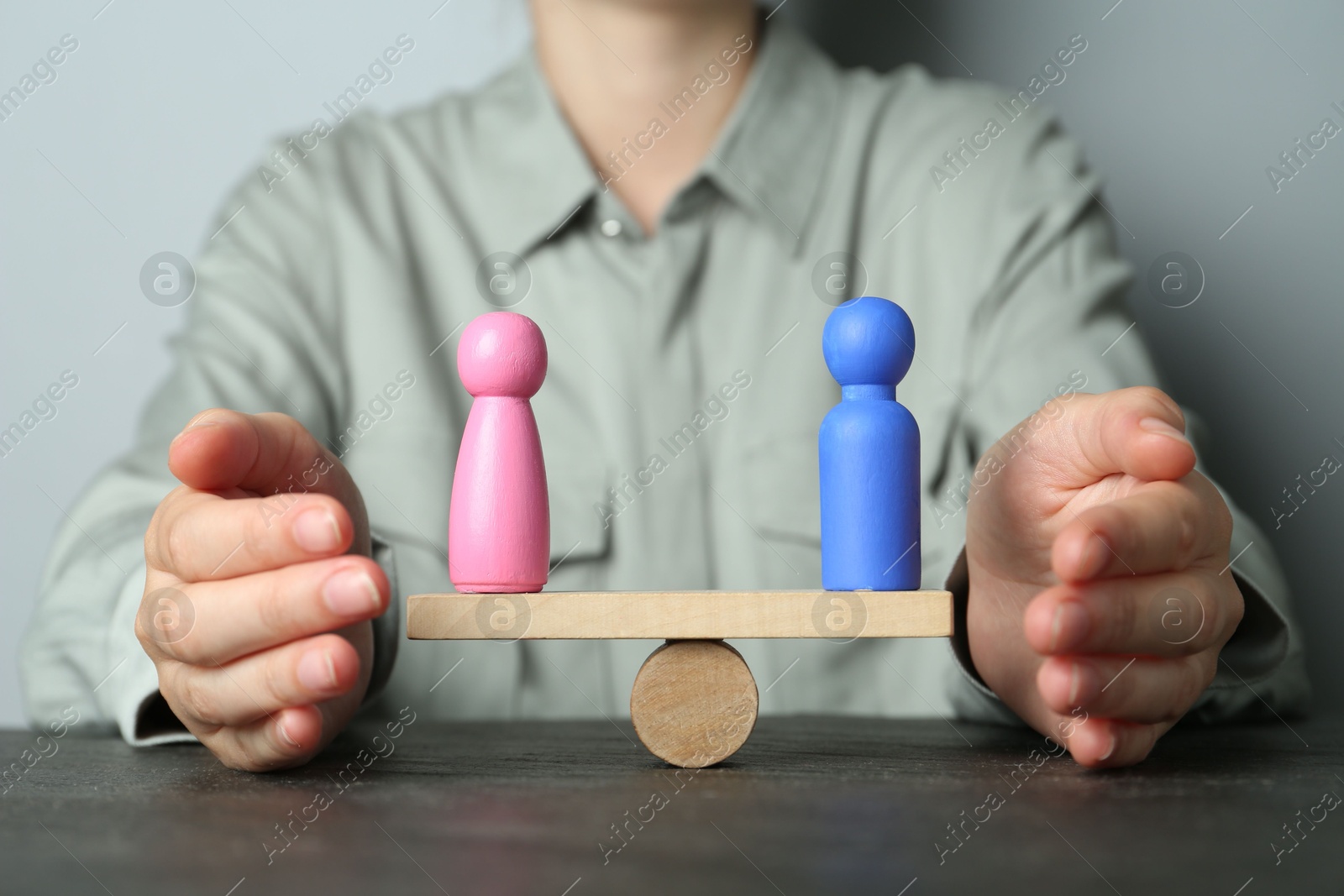 Photo of Gender equality concept. Woman with male and female figures on scales at dark table, closeup