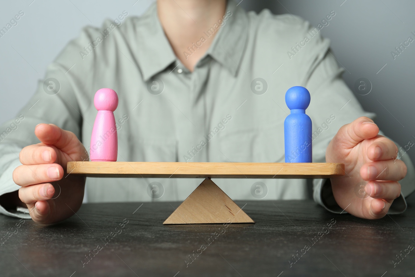 Photo of Gender equality concept. Woman with male and female figures on scales at dark table, closeup