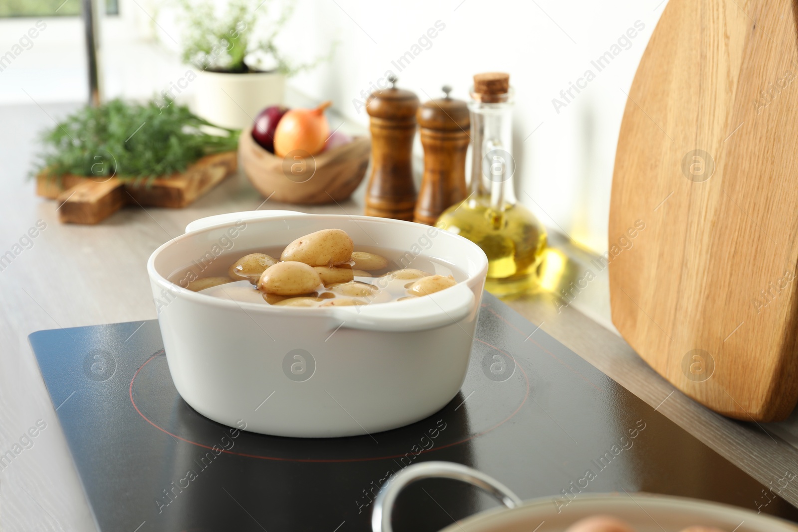 Photo of Boiling potatoes in pot on stove in kitchen