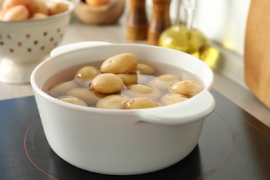 Photo of Boiling potatoes in pot on stove in kitchen