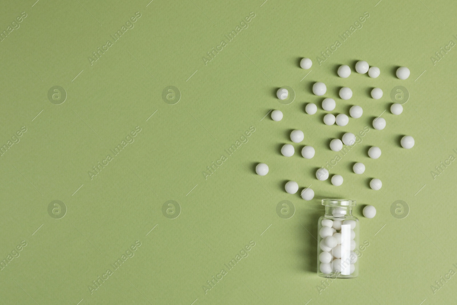 Photo of Bottle of homeopathic remedy on light green background, flat lay. Space for text