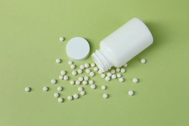 Photo of Homeopathic remedy and bottle on light green background, top view