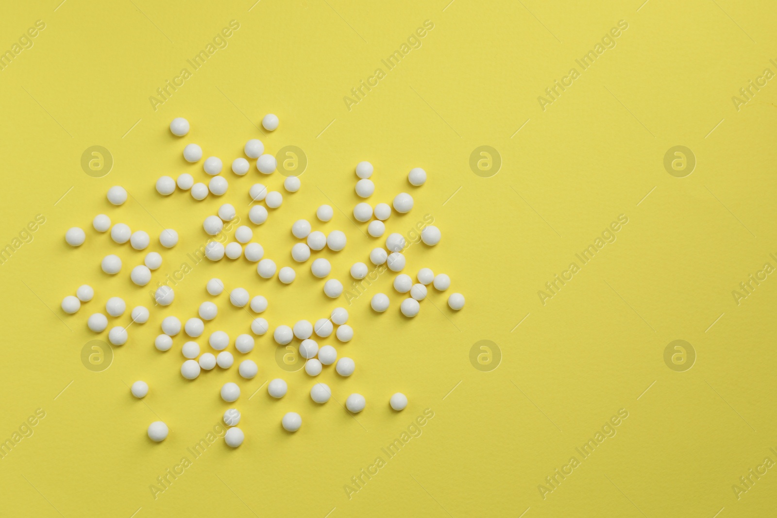 Photo of Homeopathic remedy on yellow background, flat lay. Space for text