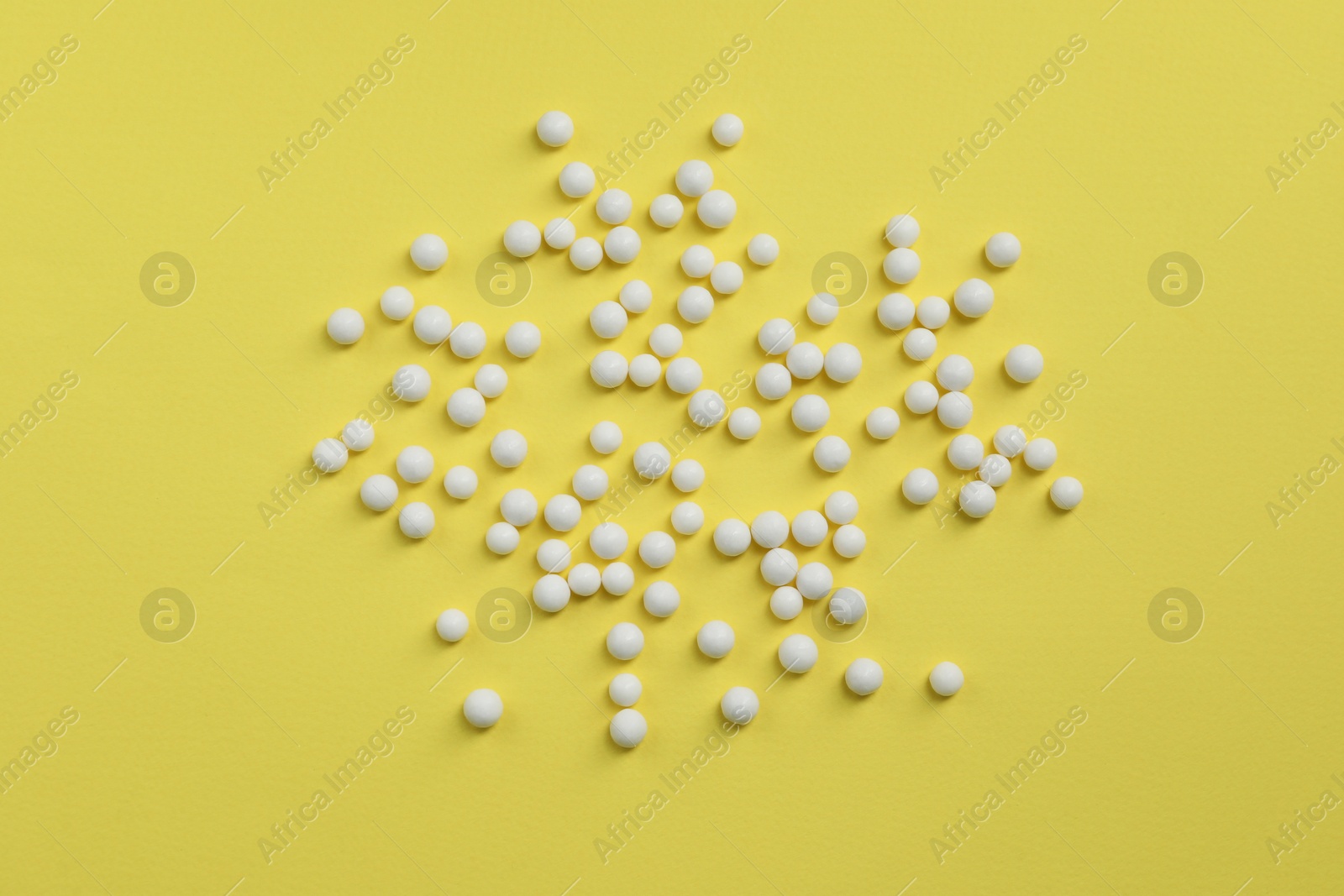 Photo of Homeopathic remedy on yellow background, flat lay