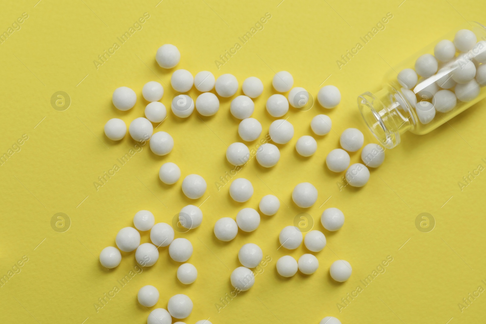 Photo of Bottle with homeopathic remedy on yellow background, top view