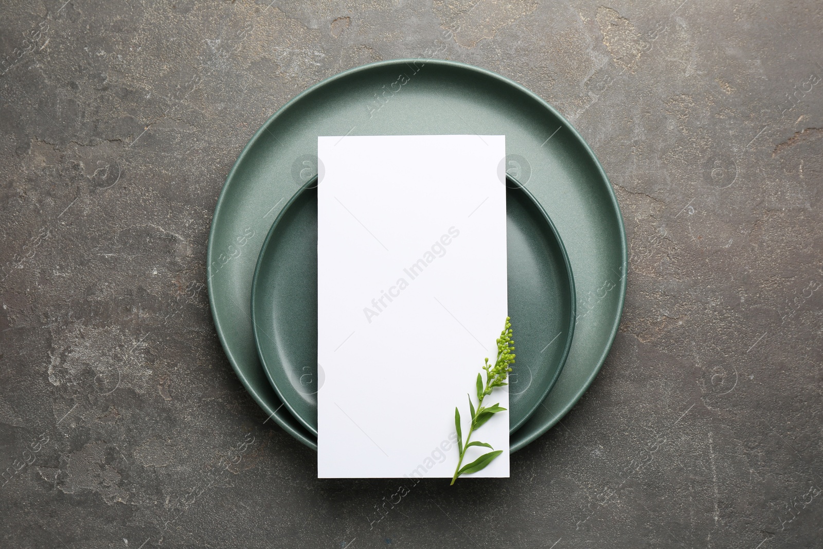 Photo of Empty menu, plates and floral decor on grey table, top view. Mockup for design