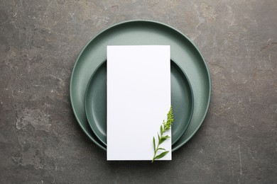 Photo of Empty menu, plates and floral decor on grey table, top view. Mockup for design