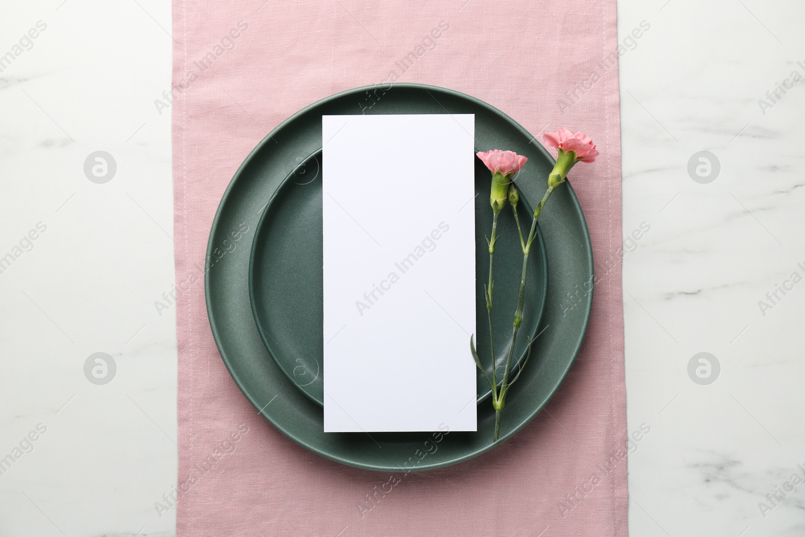 Photo of Empty menu, plates and floral decor on white marble table, top view. Mockup for design