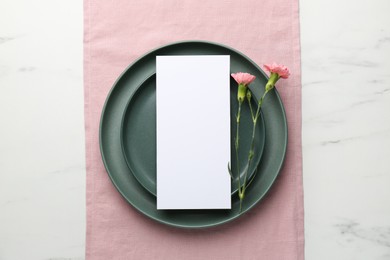 Photo of Empty menu, plates and floral decor on white marble table, top view. Mockup for design