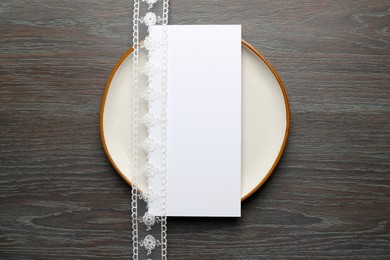 Empty menu, plate and beautiful ribbon on wooden table, top view. Mockup for design