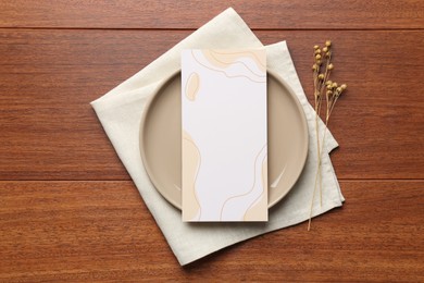 Photo of Empty menu, plate, napkin and dry flowers on wooden table, top view. Mockup for design