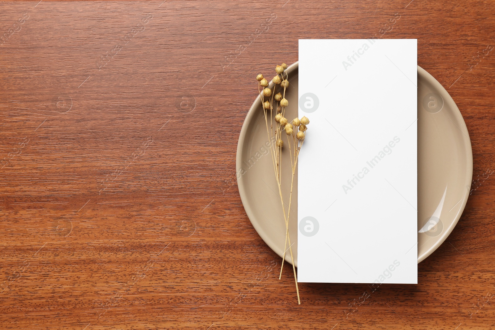 Photo of Empty menu, plate and dry flowers on wooden table, top view. Mockup for design