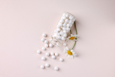 Photo of Homeopathy. Glass bottle, pills and chamomiles on beige background, top view