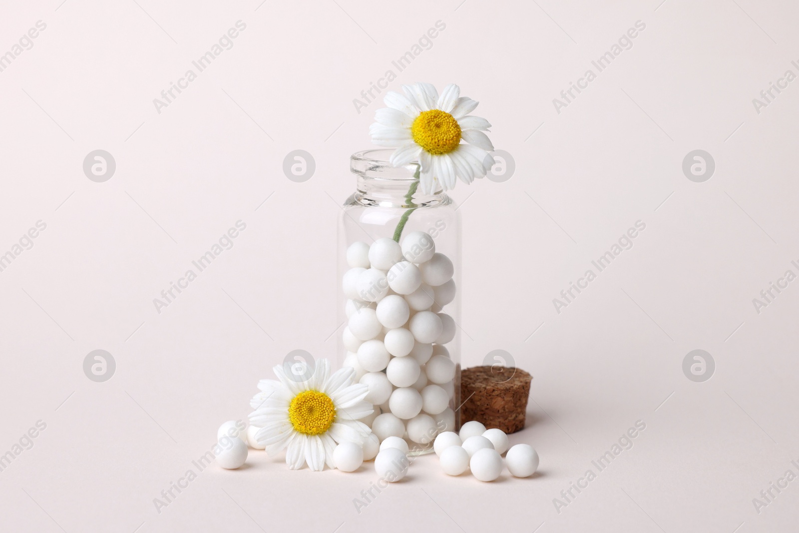 Photo of Homeopathy. Glass bottle, pills and chamomiles on beige background