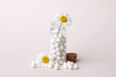 Photo of Homeopathy. Glass bottle, pills and chamomiles on beige background