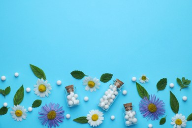 Photo of Homeopathy. Glass bottles, pills, flowers and green leaves on light blue background, flat lay. Space for text