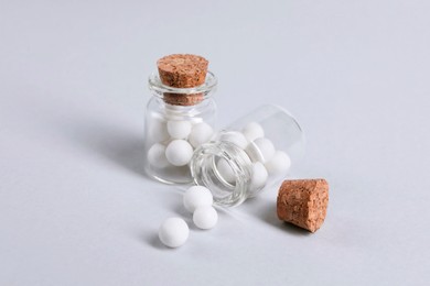 Homeopathy. Glass bottles and pills on white background