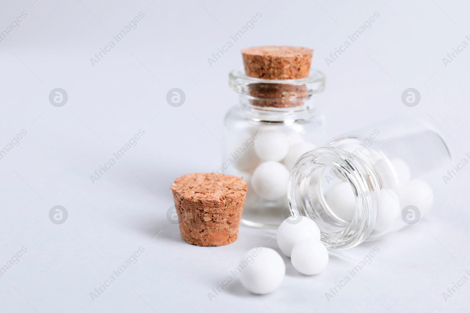 Photo of Homeopathy. Glass bottles and pills on white background, closeup. Space for text