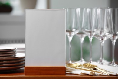 Menu holder, clean dishware and cutlery on wooden table indoors, closeup