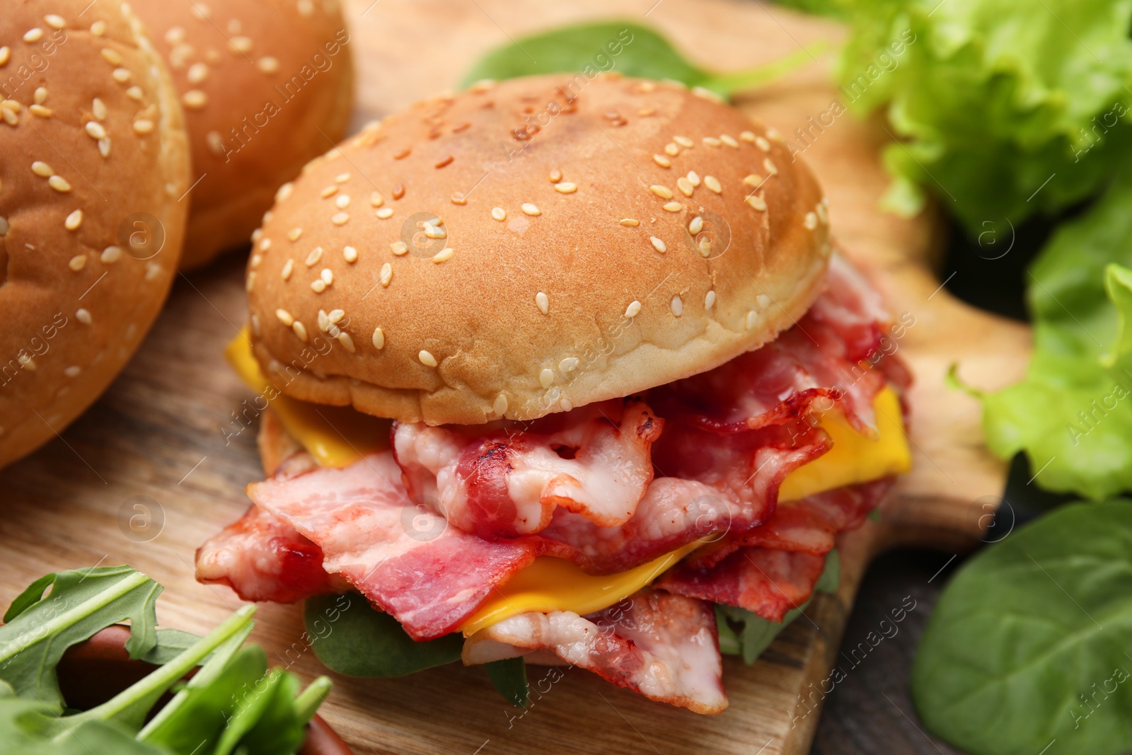 Photo of Delicious burger with bacon and cheese on table, closeup