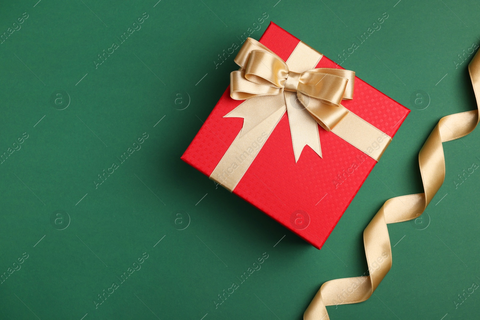 Photo of Beautiful red gift box with bow and ribbons on green background, flat lay. Space for text