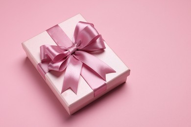 Photo of Beautiful gift box with color bow on pink background. Space for text