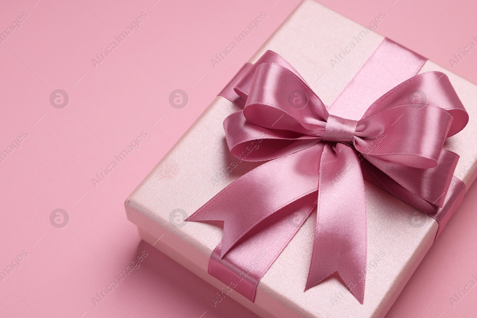 Photo of Beautiful gift box with color bow on pink background. Space for text