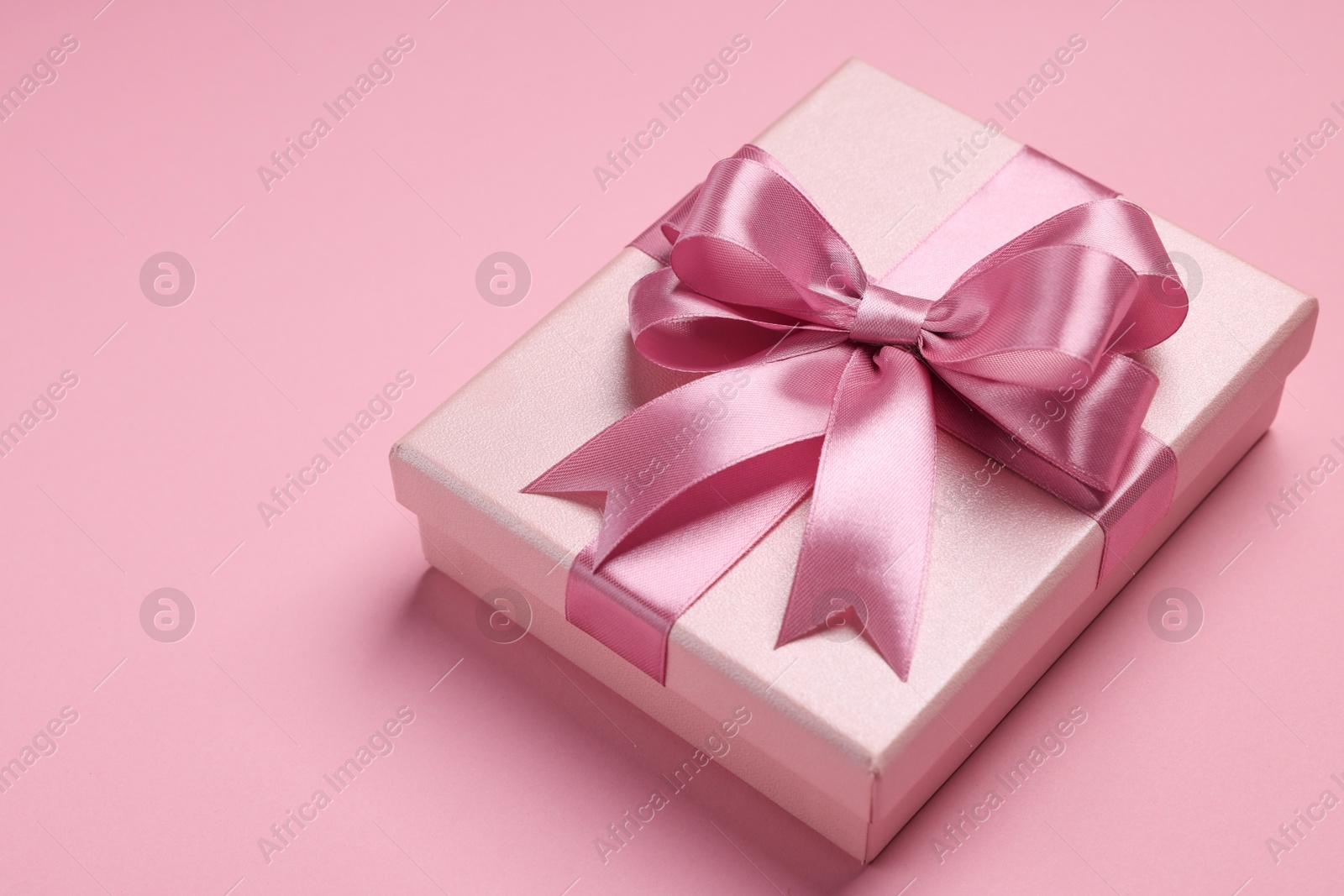 Photo of Beautiful gift box with color bow on pink background. Space for text