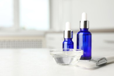 Photo of Peeling procedure. Bottles of chemical peel, bowl with liquid and brush on white table. Space for text