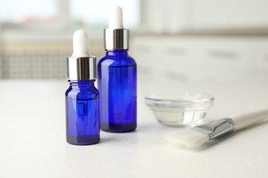 Peeling procedure. Bottles of chemical peel, bowl with liquid and brush on white table indoors