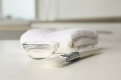 Peeling procedure. Chemical peel liquid in bowl, brush and towel on white table indoors