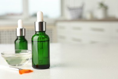 Photo of Peeling procedure. Bottles of chemical peel, bowl with liquid and brush on white table indoors. Space for text