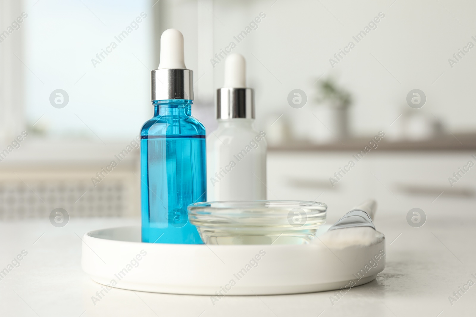 Photo of Peeling procedure. Bottles of chemical peel, bowl with liquid and brush on white table indoors