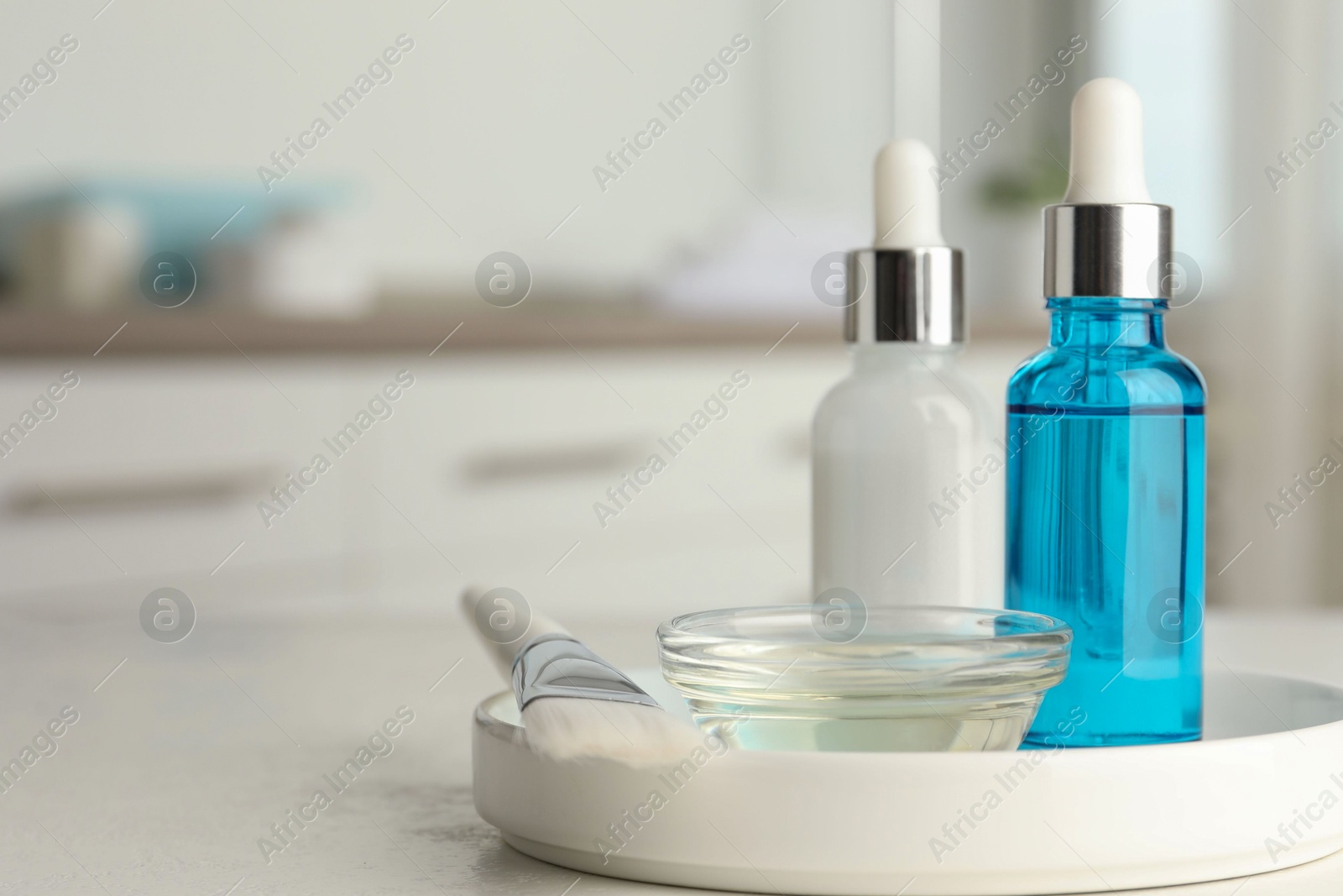 Photo of Peeling procedure. Bottles of chemical peel, bowl with liquid and brush on white table indoors. Space for text