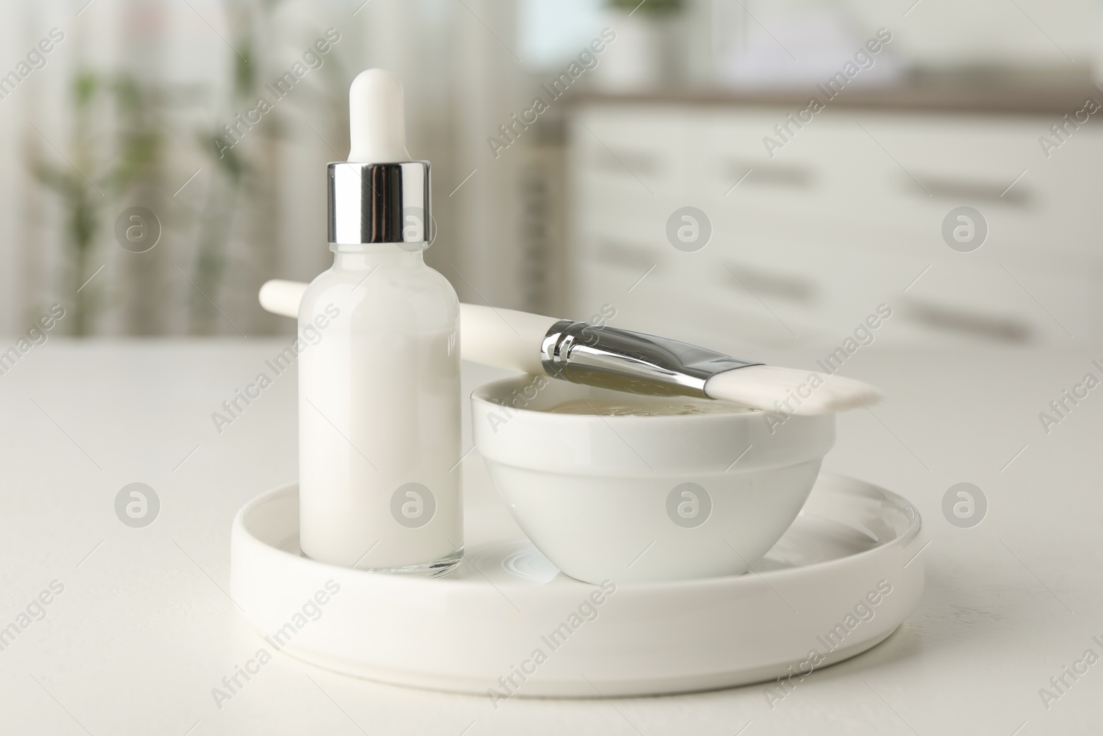 Photo of Peeling procedure. Bottle of chemical peel, bowl with liquid and brush on white table indoors