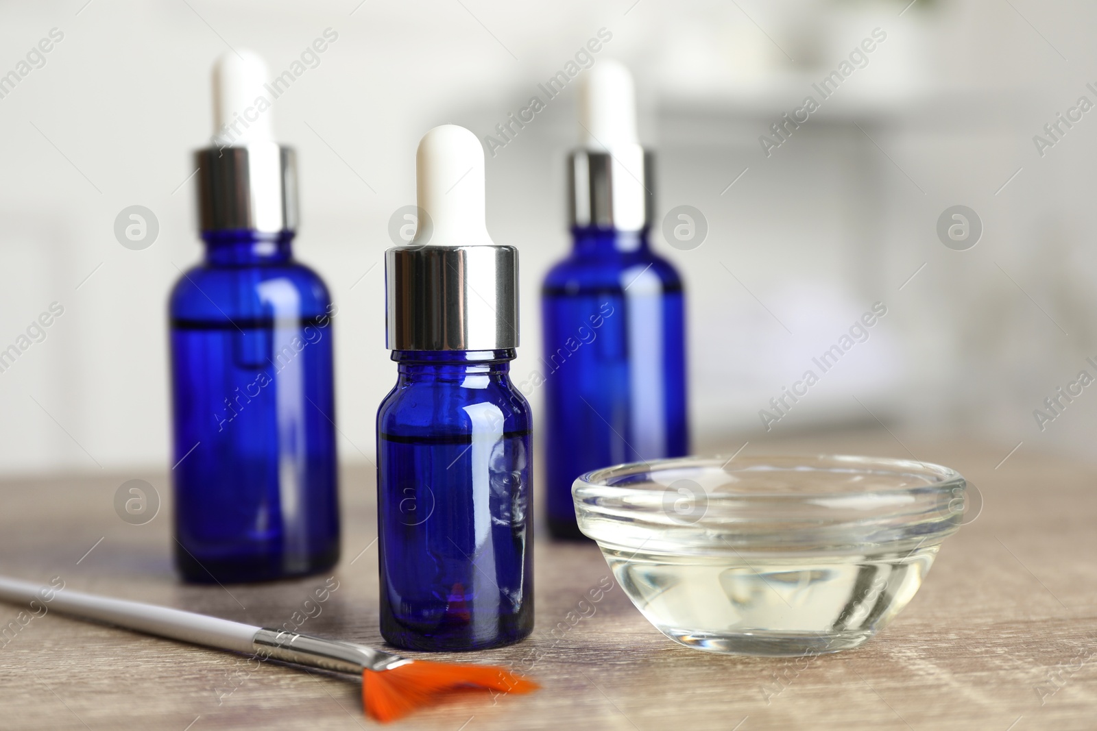 Photo of Peeling procedure. Bottles of chemical peel, bowl with liquid and brush on wooden table indoors, closeup