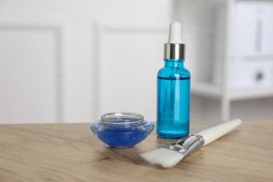 Photo of Peeling procedure. Bottle of chemical peel, bowl with liquid and brush on wooden table indoors