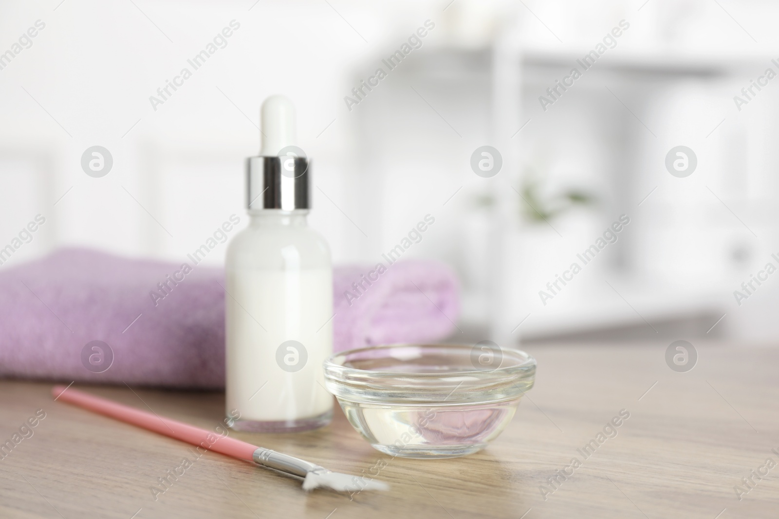 Photo of Peeling procedure. Bottle of chemical peel, bowl with liquid, towel and brush on wooden table indoors. Space for text