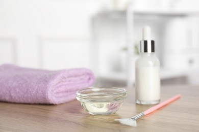 Photo of Peeling procedure. Bottle of chemical peel, bowl with liquid, towel and brush on wooden table indoors