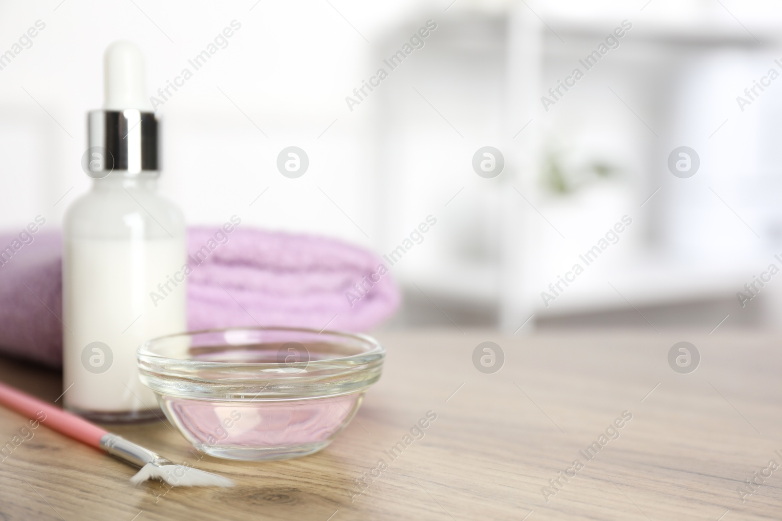 Photo of Peeling procedure. Bottle of chemical peel, bowl with liquid, towel and brush on wooden table indoors. Space for text