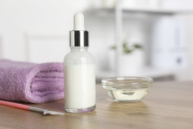 Photo of Peeling procedure. Bottle of chemical peel, bowl with liquid, towel and brush on wooden table indoors. Space for text