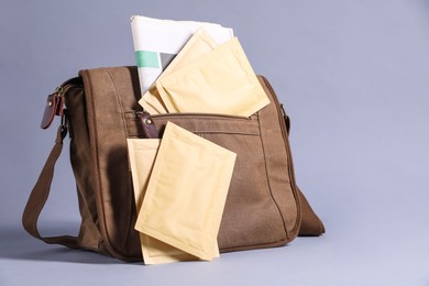 Photo of Brown postman's bag with envelopes and newspapers on grey background